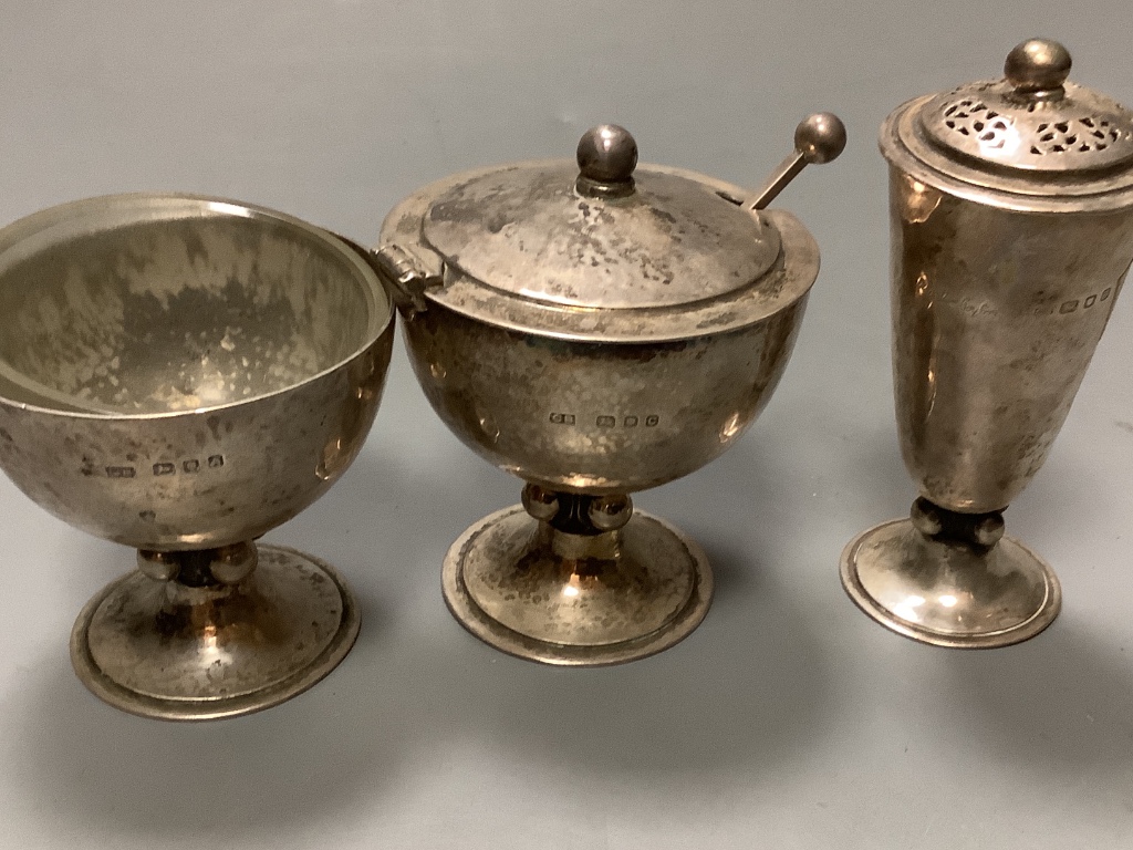 A stylish Art Deco planished silver three piece condiment set and matching spoon, by Charles Boyton, London, 1936/7 & 8, tallest piece 9cm, 9oz.